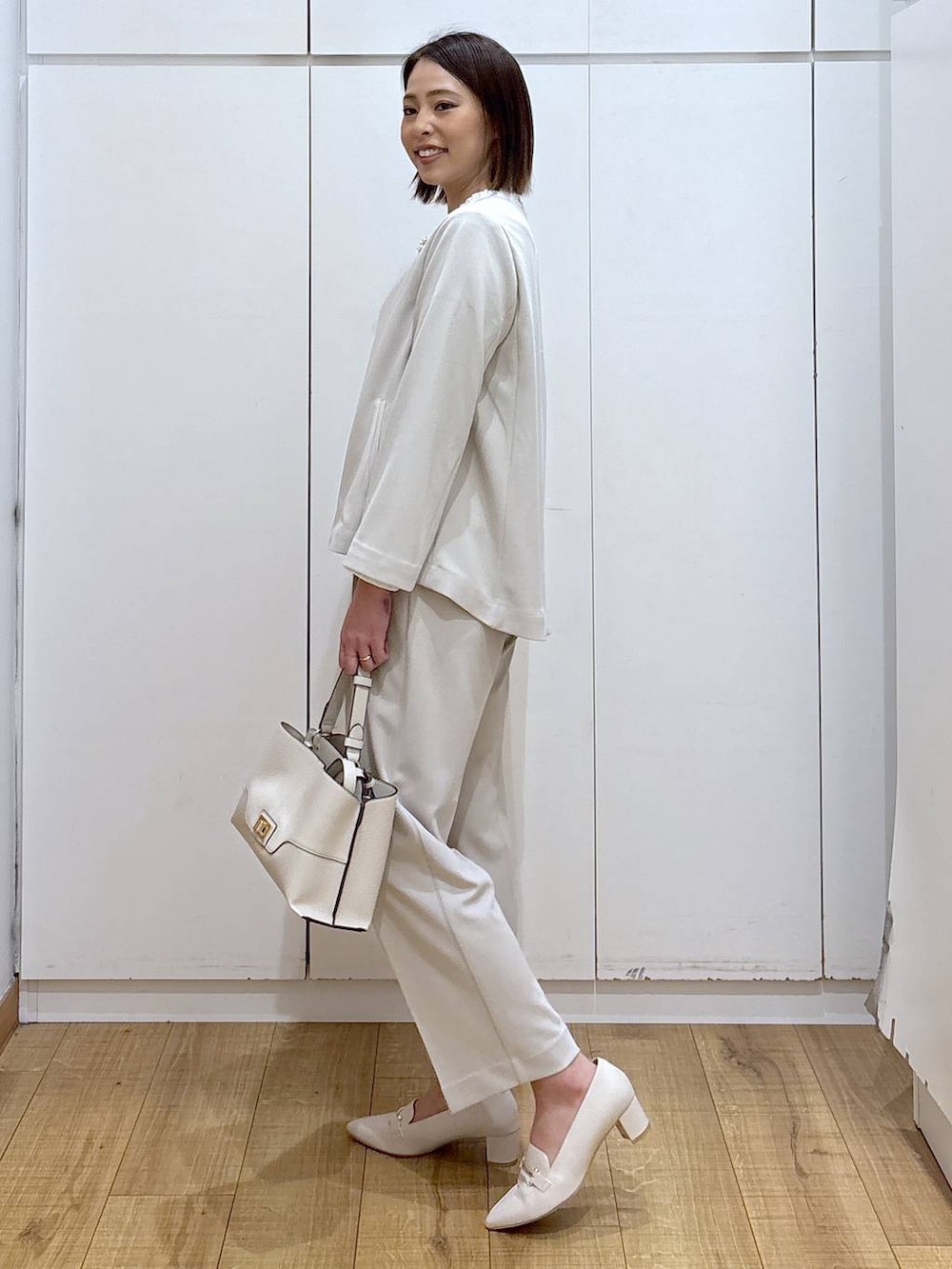 ベージュ系のセットアップ、ベージュ系のショルダーバッグ、ホワイト系のローファーを着用したレディースの冬コーディネートの4枚目の写真