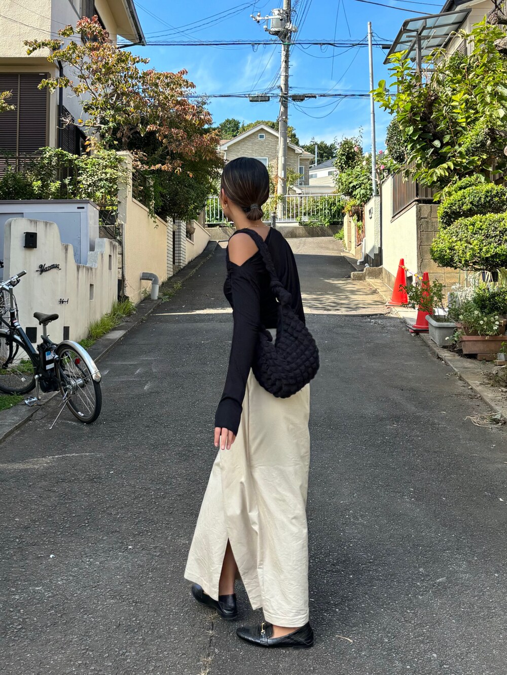 ブラック系のTシャツ/カットソー、ブラック系のショルダーバッグ、ベージュ系のスカートを着用したレディースの秋コーディネートの2枚目の写真