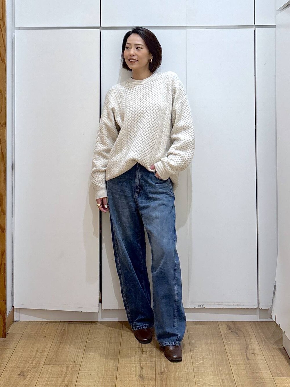 ブラウン系のブーツ、ホワイト系のニット/セーター、ブルー系のデニムパンツを着用したレディースの冬コーディネートの2枚目の写真