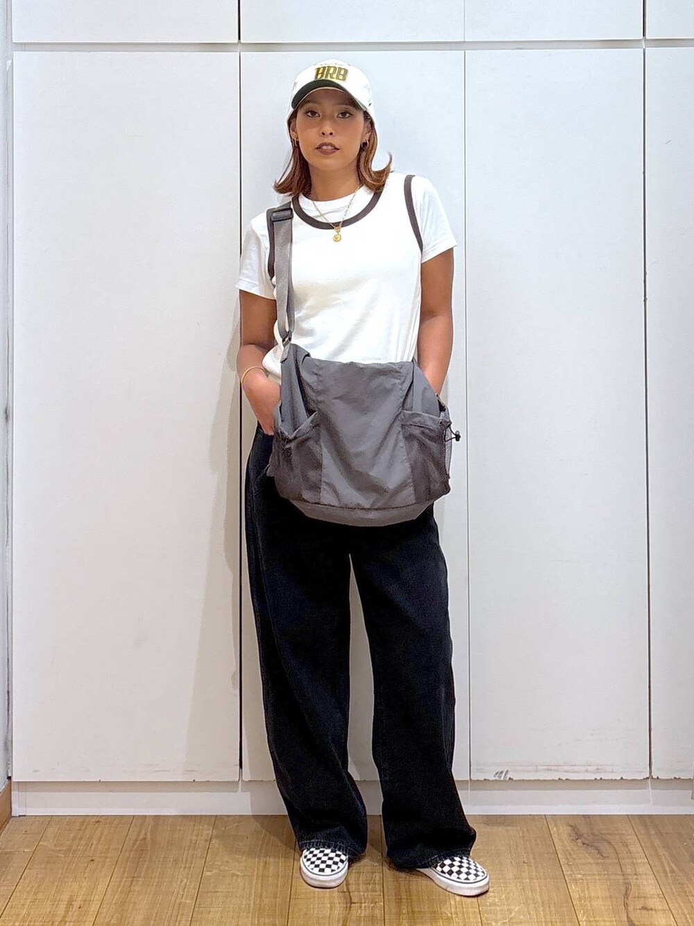 グレー系のトートバッグ、ブラック系のデニムパンツ、ホワイト系のタンクトップを着用したレディースの夏コーディネートの3枚目の写真