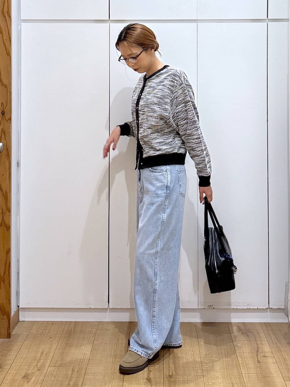 ブラック系のボストンバッグ、ブルー系のデニムパンツ、ベージュ系のローファーを着用したレディースの秋コーディネートの5枚目の写真