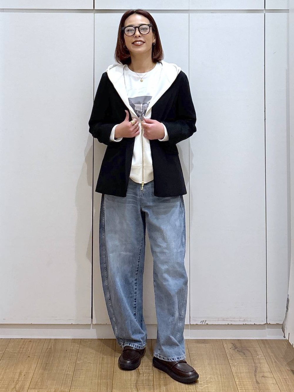 ホワイト系のパーカー、ブラック系のノーカラージャケット、ブルー系のデニムパンツを着用したレディースの春コーディネートの3枚目の写真