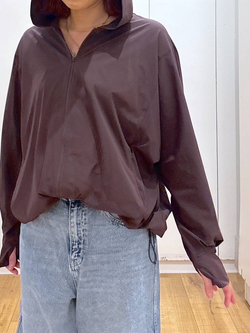 ブルー系のデニムパンツ、ブラウン系のマウンテンパーカー、ブルー系のキャップを着用したレディースの夏コーディネートの7枚目の写真