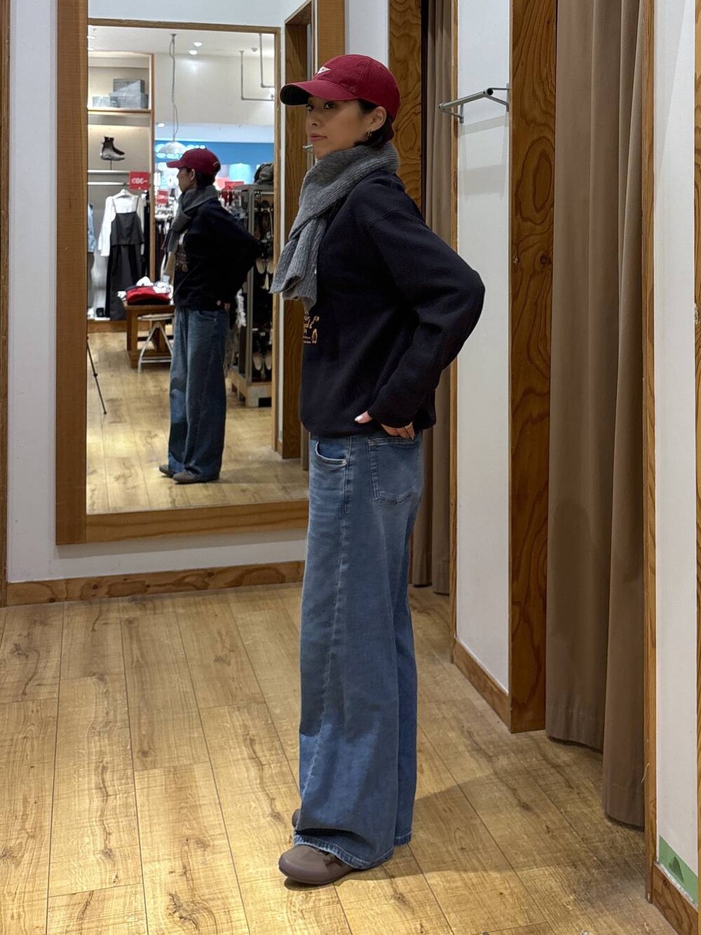 グレー系のスウェット、ブルー系のデニムパンツ、レッド系のハットを着用したレディースの秋コーディネートの3枚目の写真