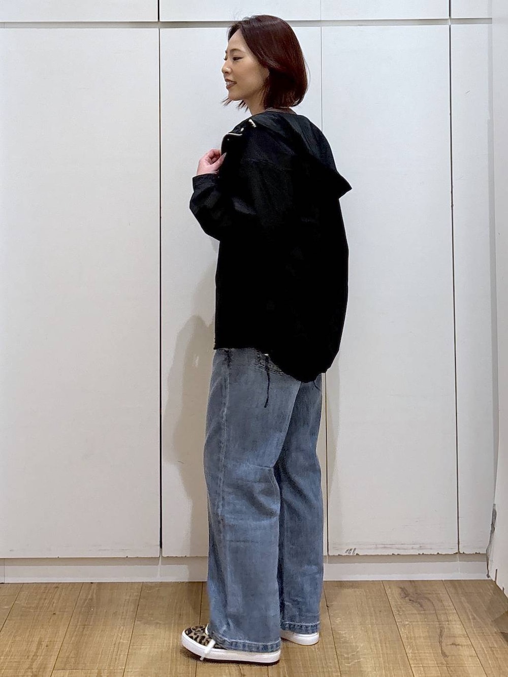 ブルー系のデニムパンツ、ブラック系のマウンテンパーカー、ブラウン系のカーディガン/ボレロを着用したレディースの春コーディネートの4枚目の写真