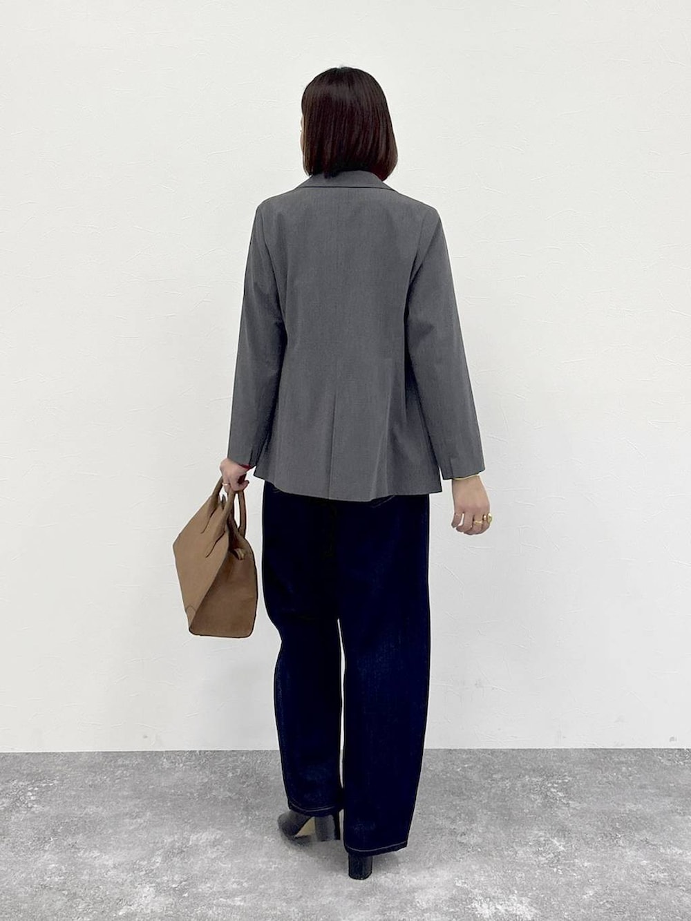 ブラウン系のトートバッグ、グレー系のテーラードジャケット、ブラック系のブーツを着用したレディースの冬コーディネートの6枚目の写真