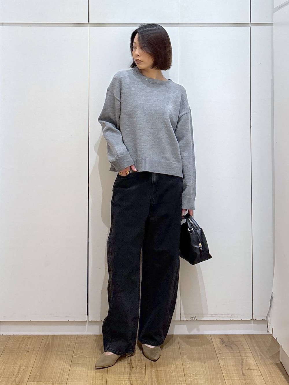 ブラック系のショルダーバッグ、ベージュ系のパンプス、ブラック系のデニムパンツを着用したレディースの冬コーディネートの2枚目の写真