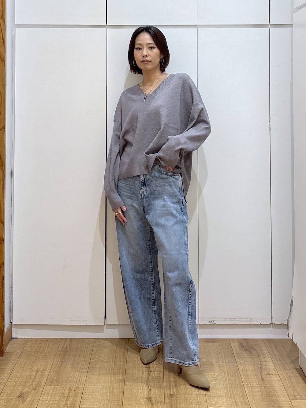 グレー系のニット/セーター、ベージュ系のブーツ、ブルー系のデニムパンツを着用したレディースの冬コーディネートの3枚目の写真