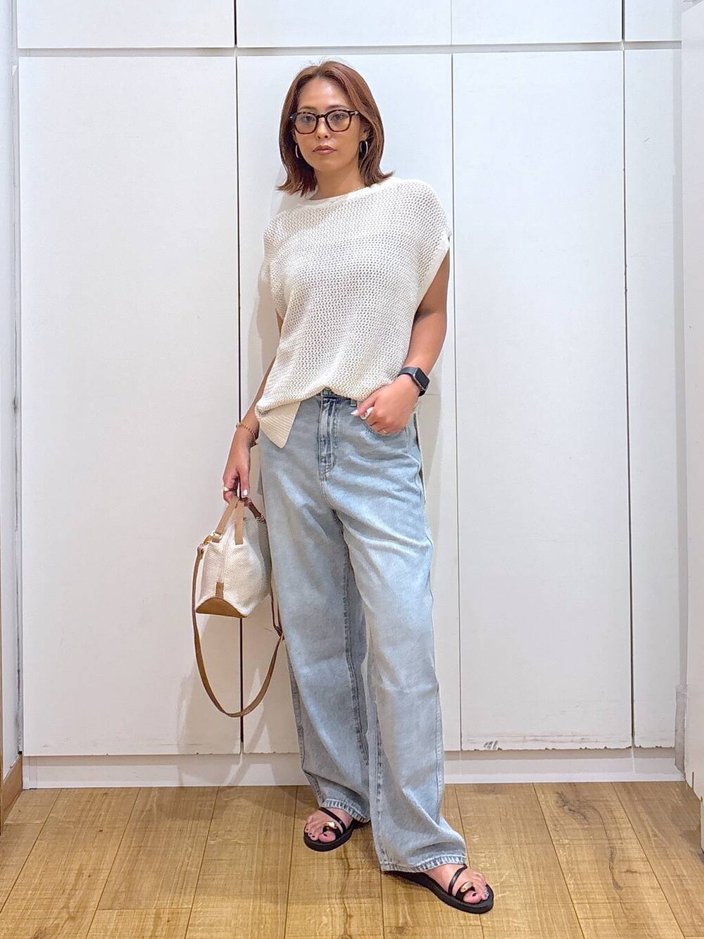 ブルー系のデニムパンツ、ホワイト系のショルダーバッグ、ブラック系のキャミソールを着用したレディースの夏コーディネートの2枚目の写真