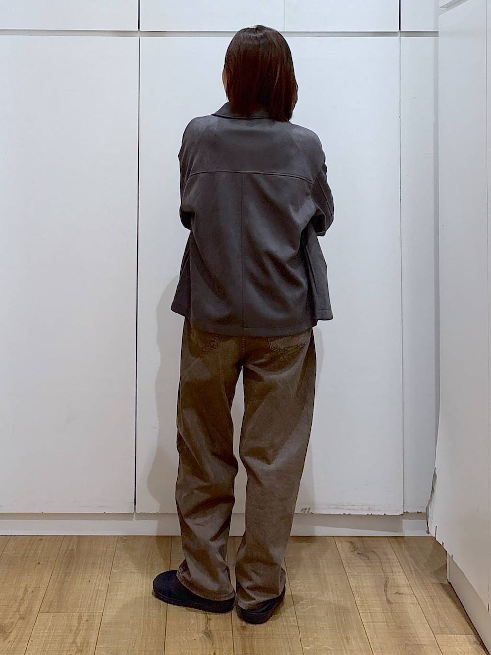 グレー系のニット/セーター、グレー系のテーラードジャケット、ブラウン系のデニムパンツを着用したレディースの冬コーディネートの5枚目の写真