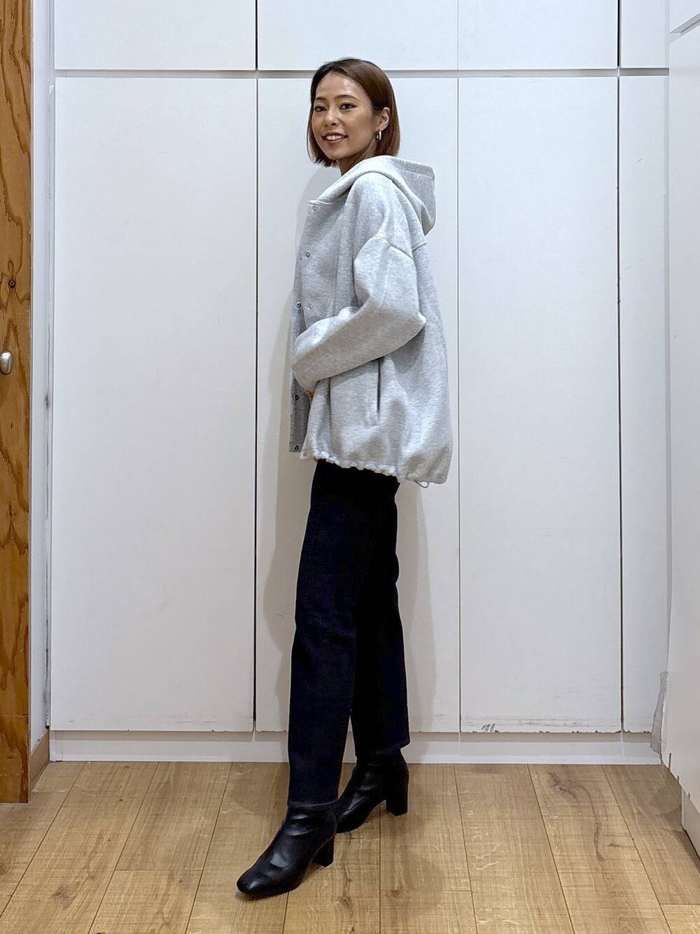 ブルー系のデニムパンツ、ブラック系のニット/セーター、グレー系のブルゾンを着用したレディースの秋コーディネートの2枚目の写真