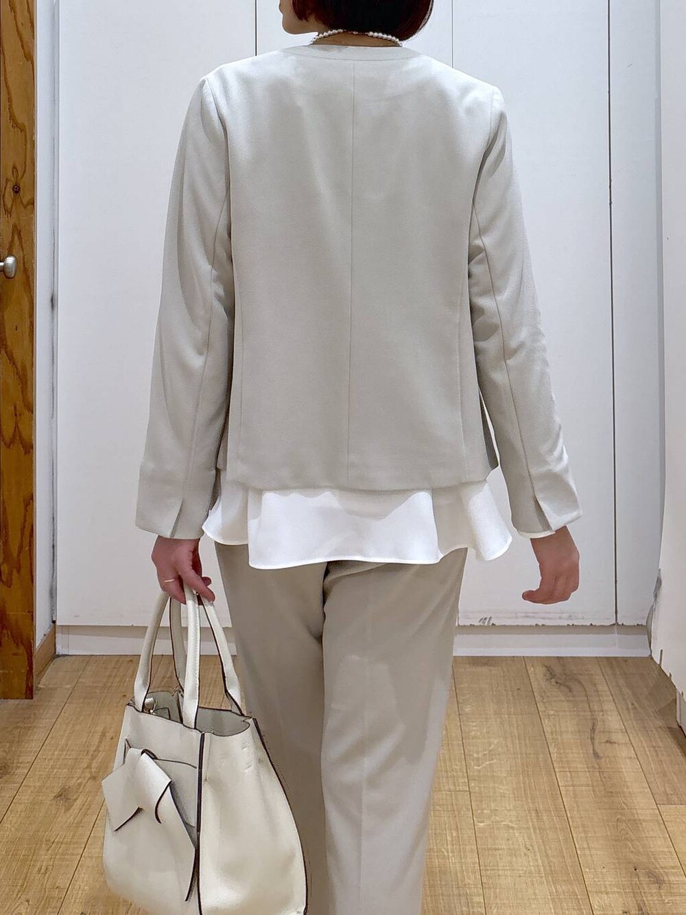 ホワイト系のパンプス、ベージュ系のセットアップ、ベージュ系のハンドバッグを着用したレディースの冬コーディネートの9枚目の写真