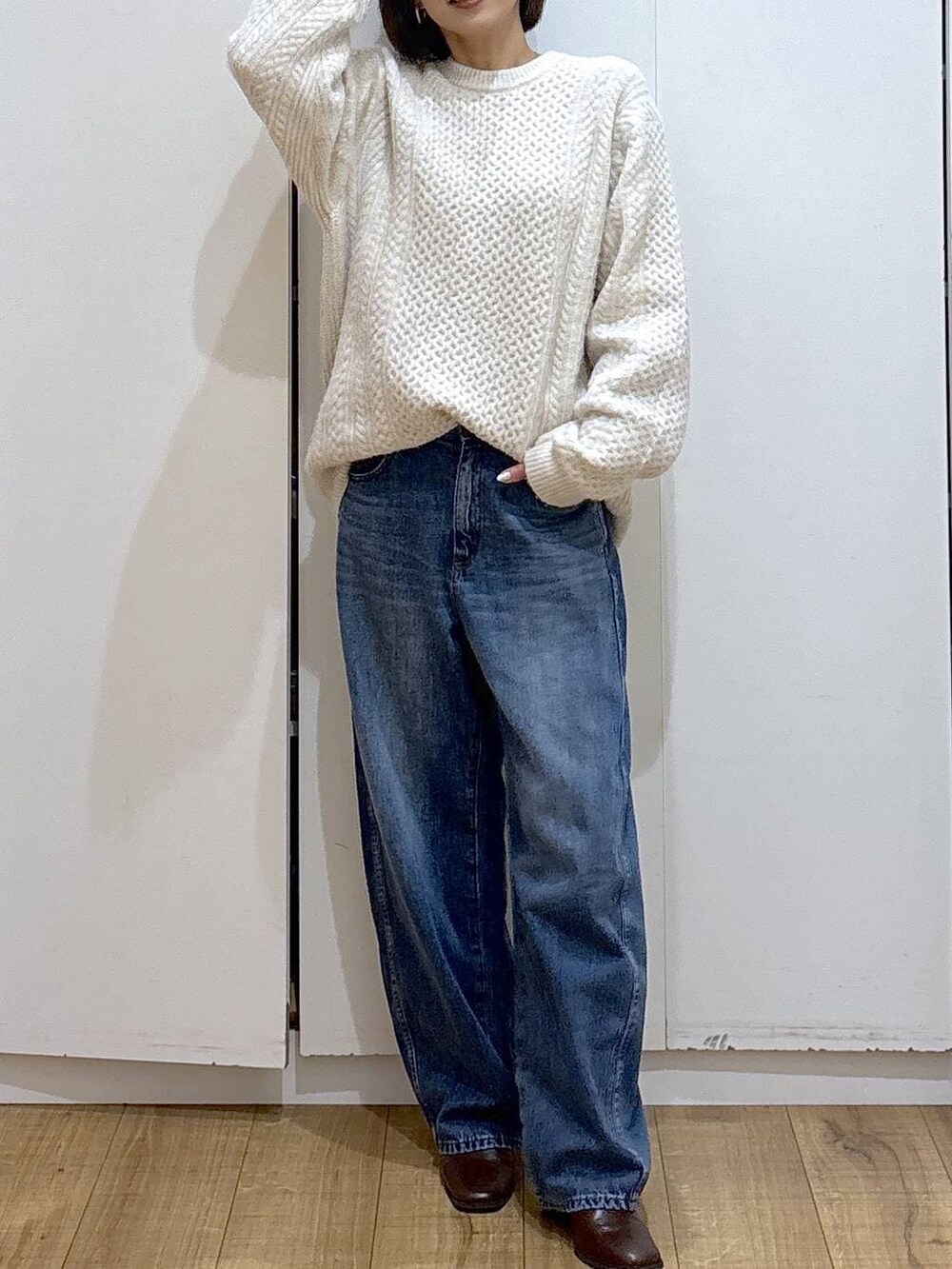 ブラウン系のブーツ、ホワイト系のニット/セーター、ブルー系のデニムパンツを着用したレディースの冬コーディネートの4枚目の写真