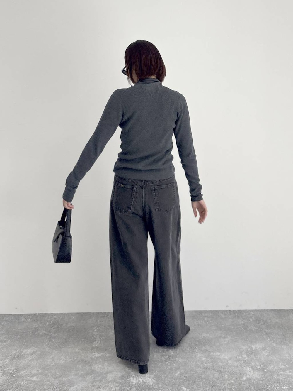 ブラック系のデニムパンツ、ブラック系のブーツ、グレー系のニット/セーターを着用したレディースの秋コーディネートの6枚目の写真