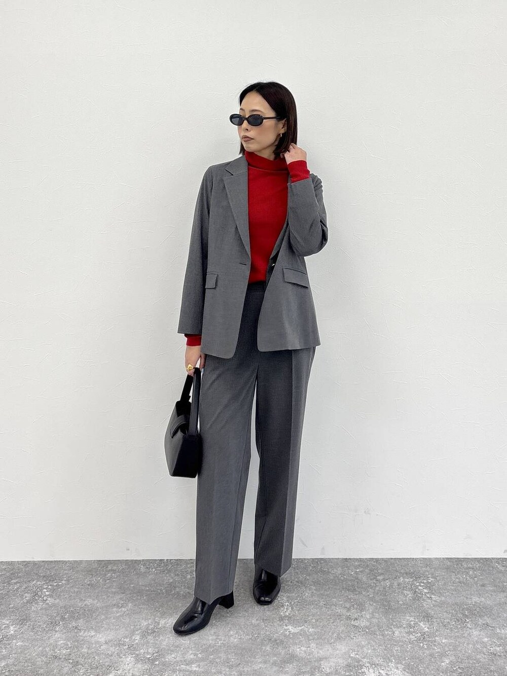 グレー系のスラックス、グレー系のテーラードジャケット、ブラック系のブーツを着用したレディースの冬コーディネートの3枚目の写真