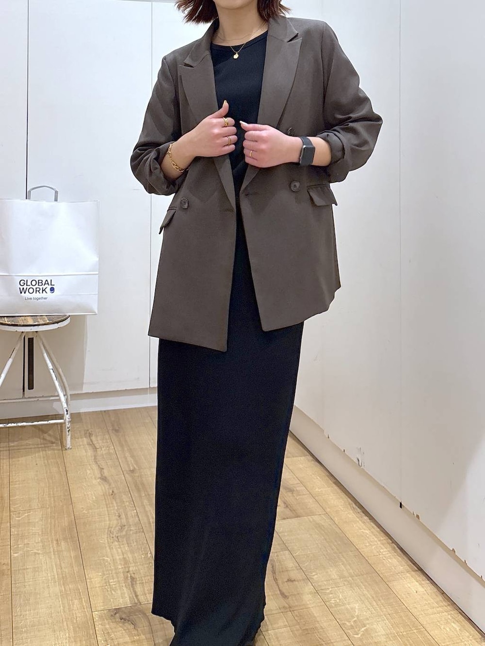 ブラウン系のテーラードジャケット、ブラック系のスカート、ゴールド系のネックレスを着用したレディースの春コーディネートの4枚目の写真