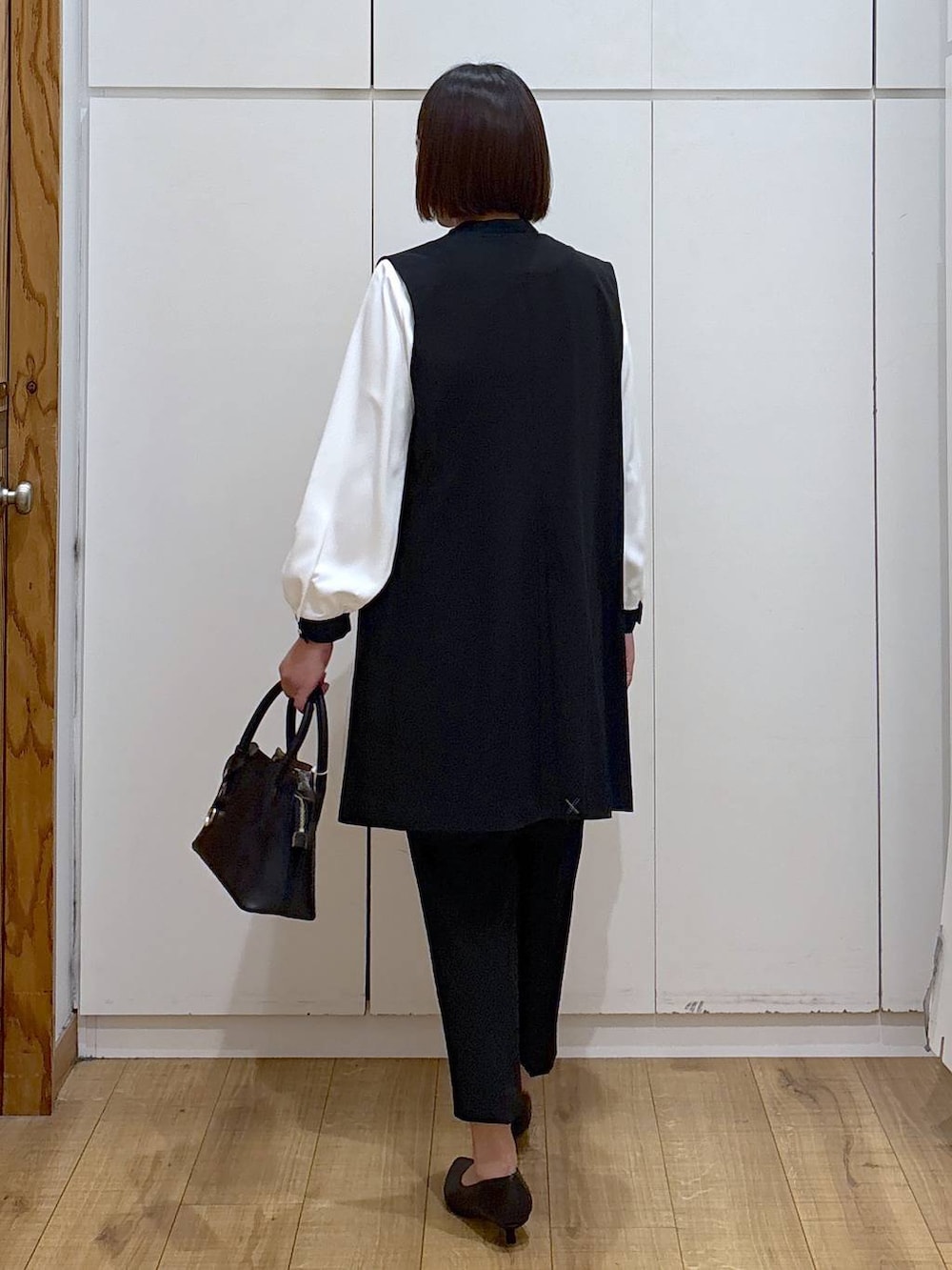 ブラック系のショルダーバッグ、ブラック系のパンプス、ブラック系のスラックスを着用したレディースの冬コーディネートの7枚目の写真