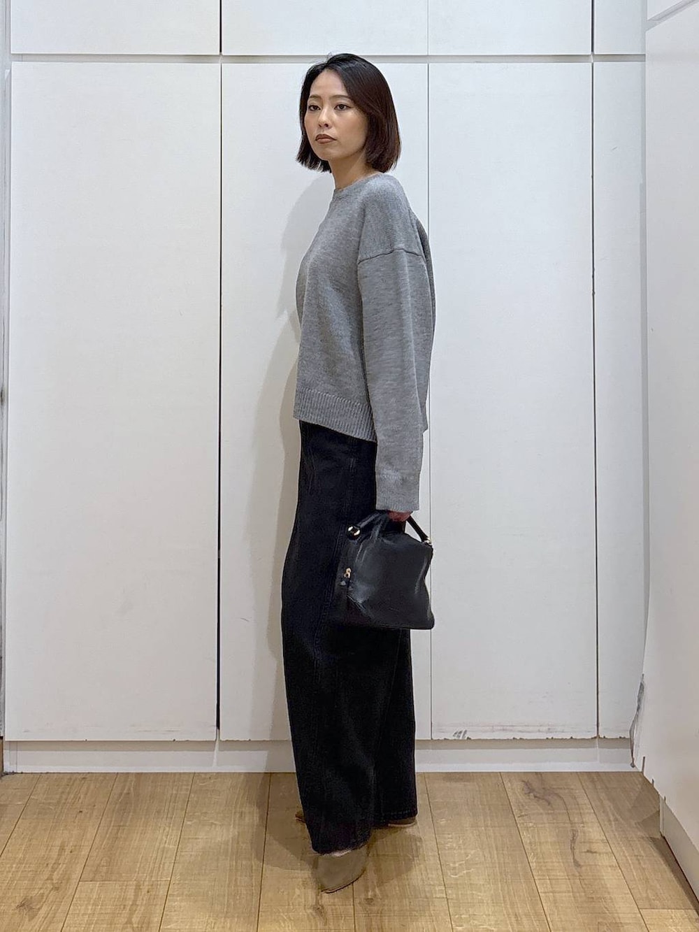 ブラック系のショルダーバッグ、ベージュ系のパンプス、ブラック系のデニムパンツを着用したレディースの冬コーディネートの4枚目の写真