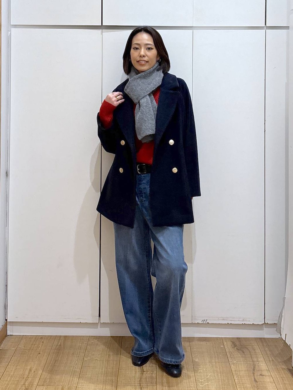 ブルー系のチェスターコート、ブラック系のブーツ、ブルー系のデニムパンツを着用したレディースの秋コーディネートの2枚目の写真