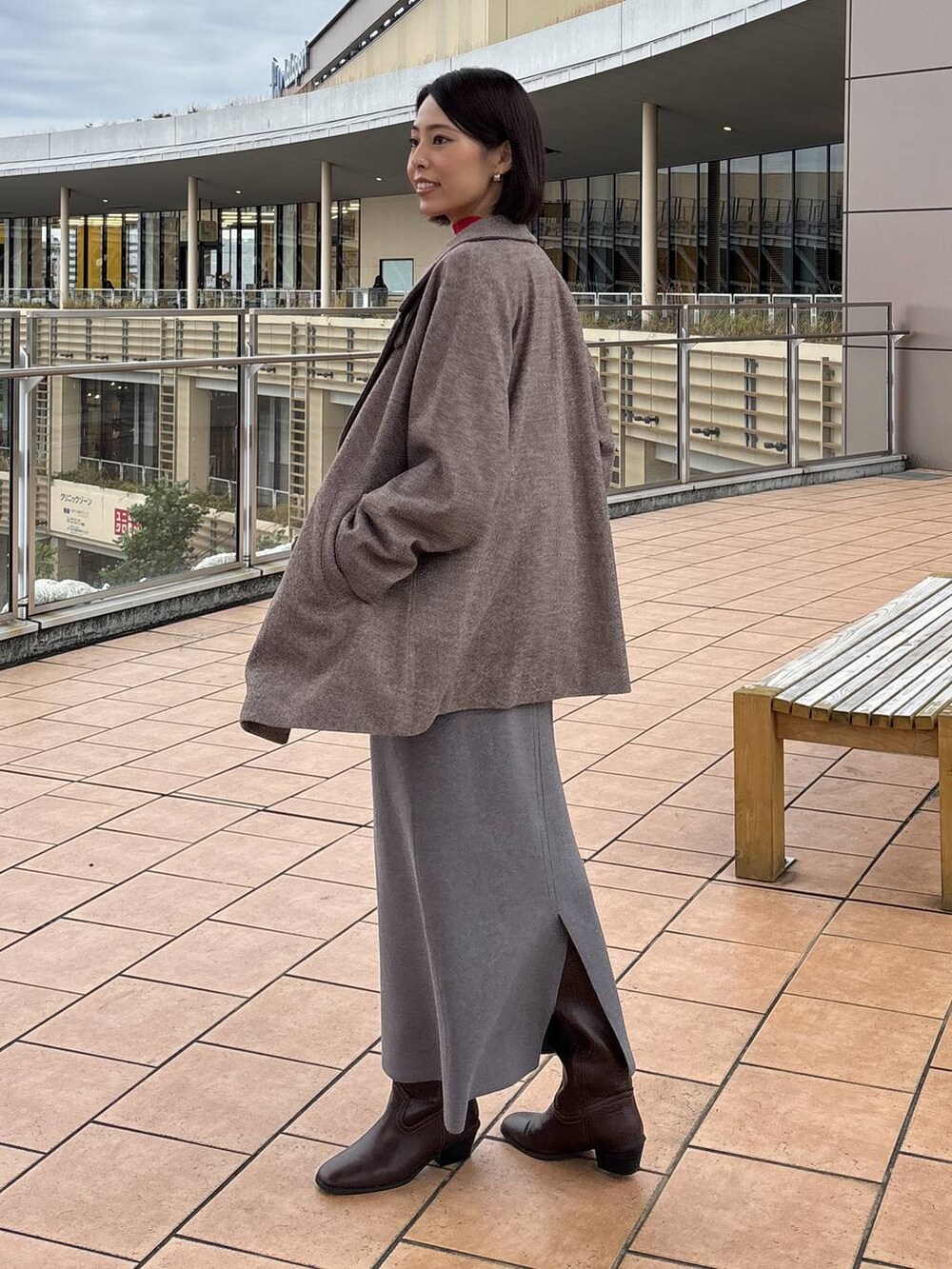 ブラウン系のチェスターコート、グレー系のスカート、ホワイト系のTシャツ/カットソーを着用したレディースの秋コーディネートの2枚目の写真