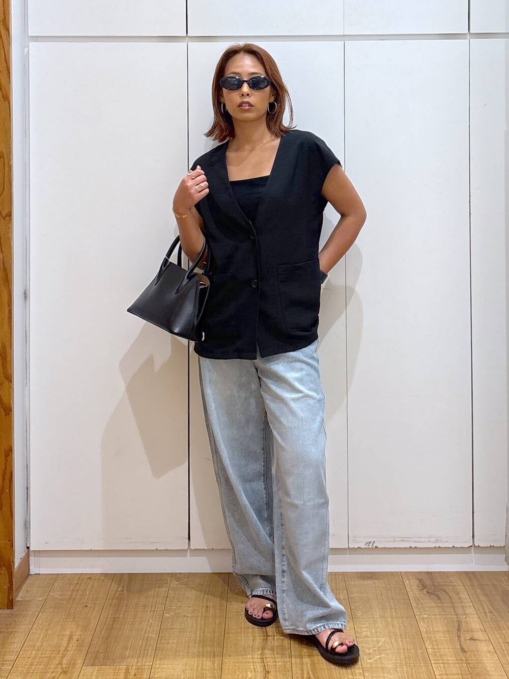 ブルー系のデニムパンツ、ブラック系のショルダーバッグ、ブラック系のキャミソールを着用したレディースの夏コーディネートの3枚目の写真