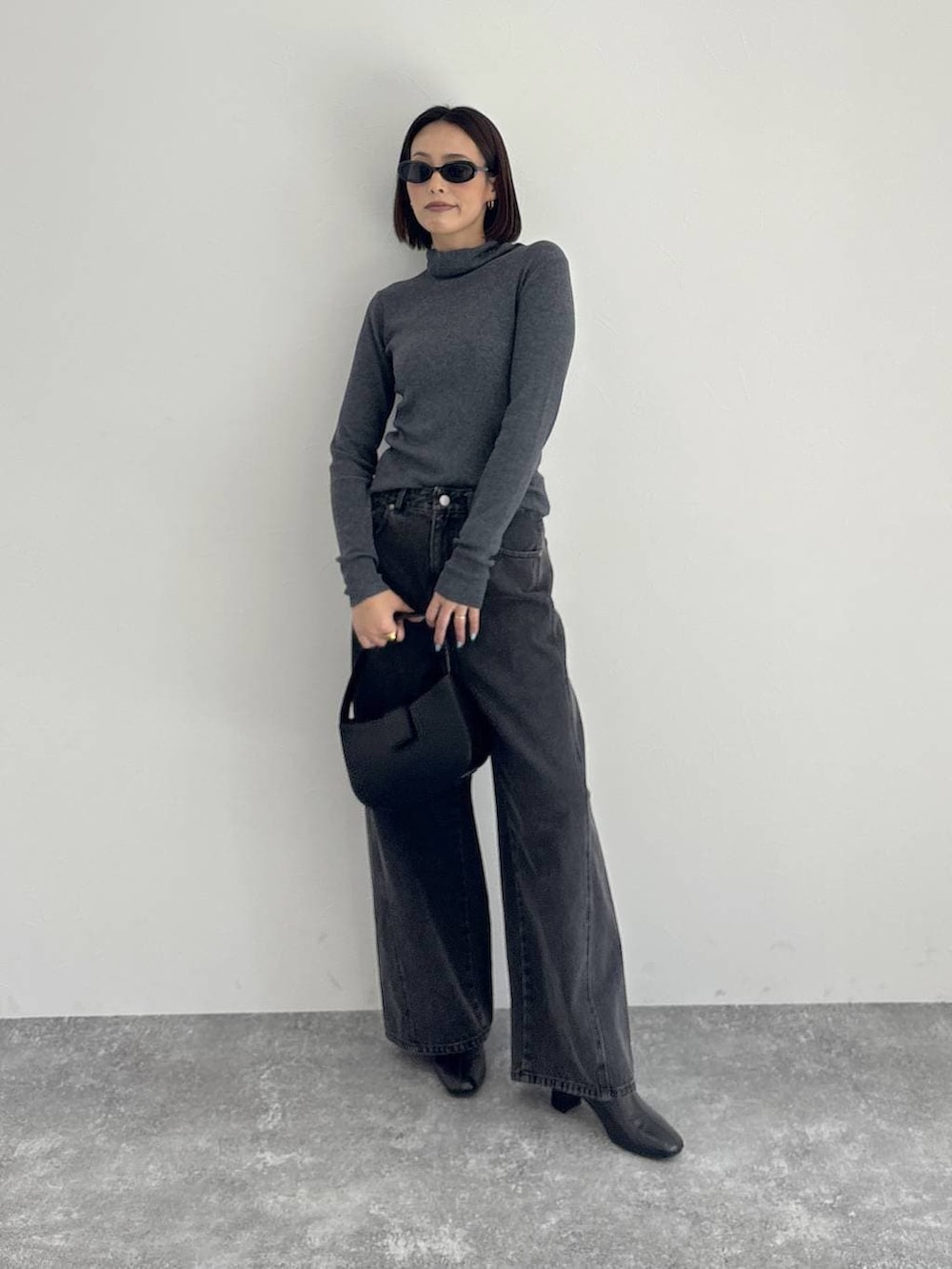 ブラック系のデニムパンツ、ブラック系のブーツ、グレー系のニット/セーターを着用したレディースの秋コーディネートの3枚目の写真