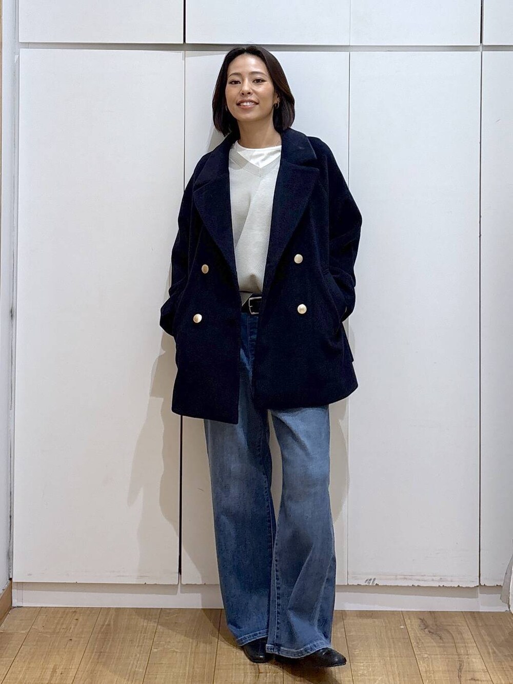 ブルー系のチェスターコート、ベージュ系のスウェット、ブラック系のブーツを着用したレディースの秋コーディネートの3枚目の写真