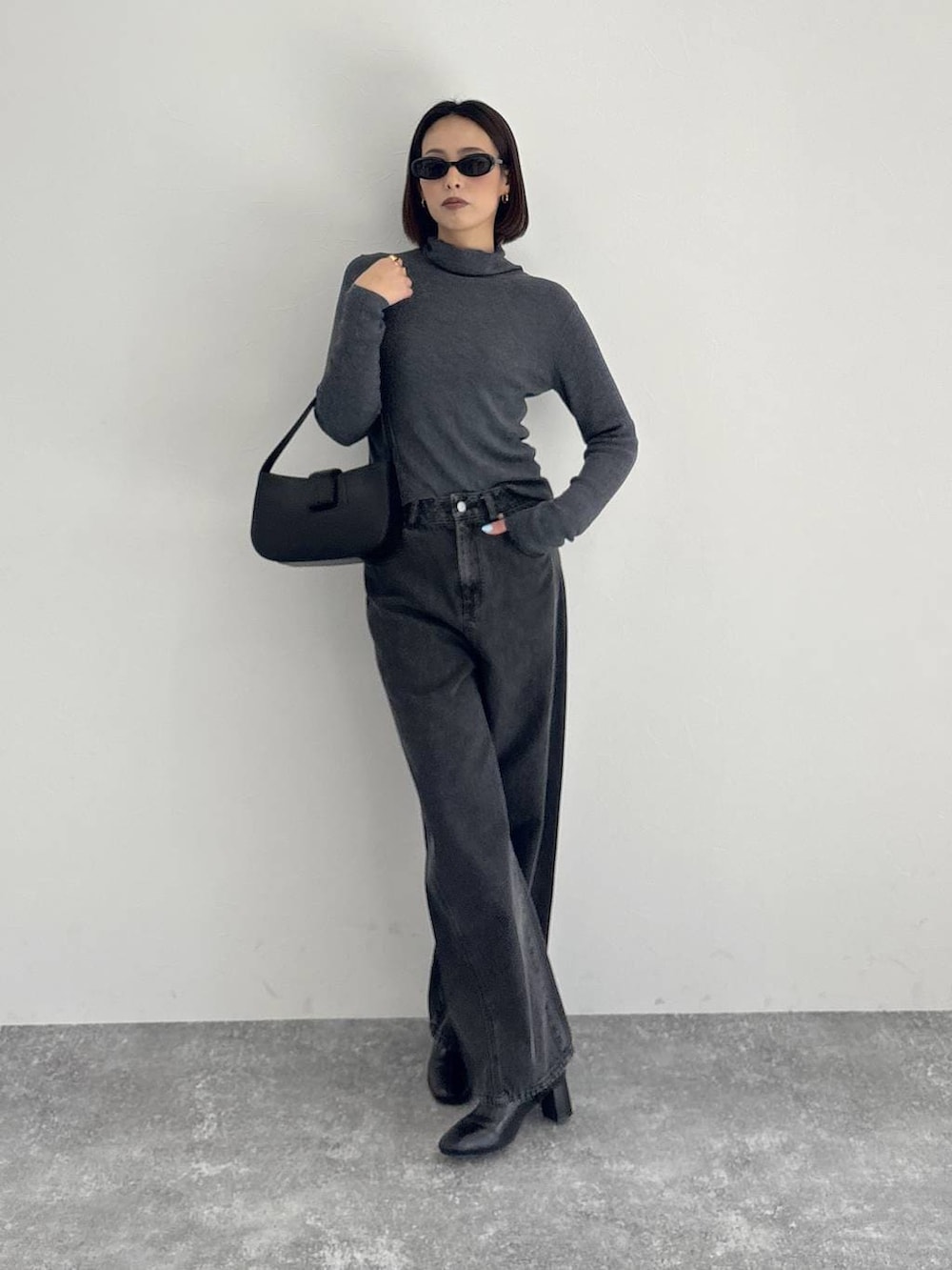 ブラック系のデニムパンツ、ブラック系のブーツ、グレー系のニット/セーターを着用したレディースの秋コーディネートの4枚目の写真