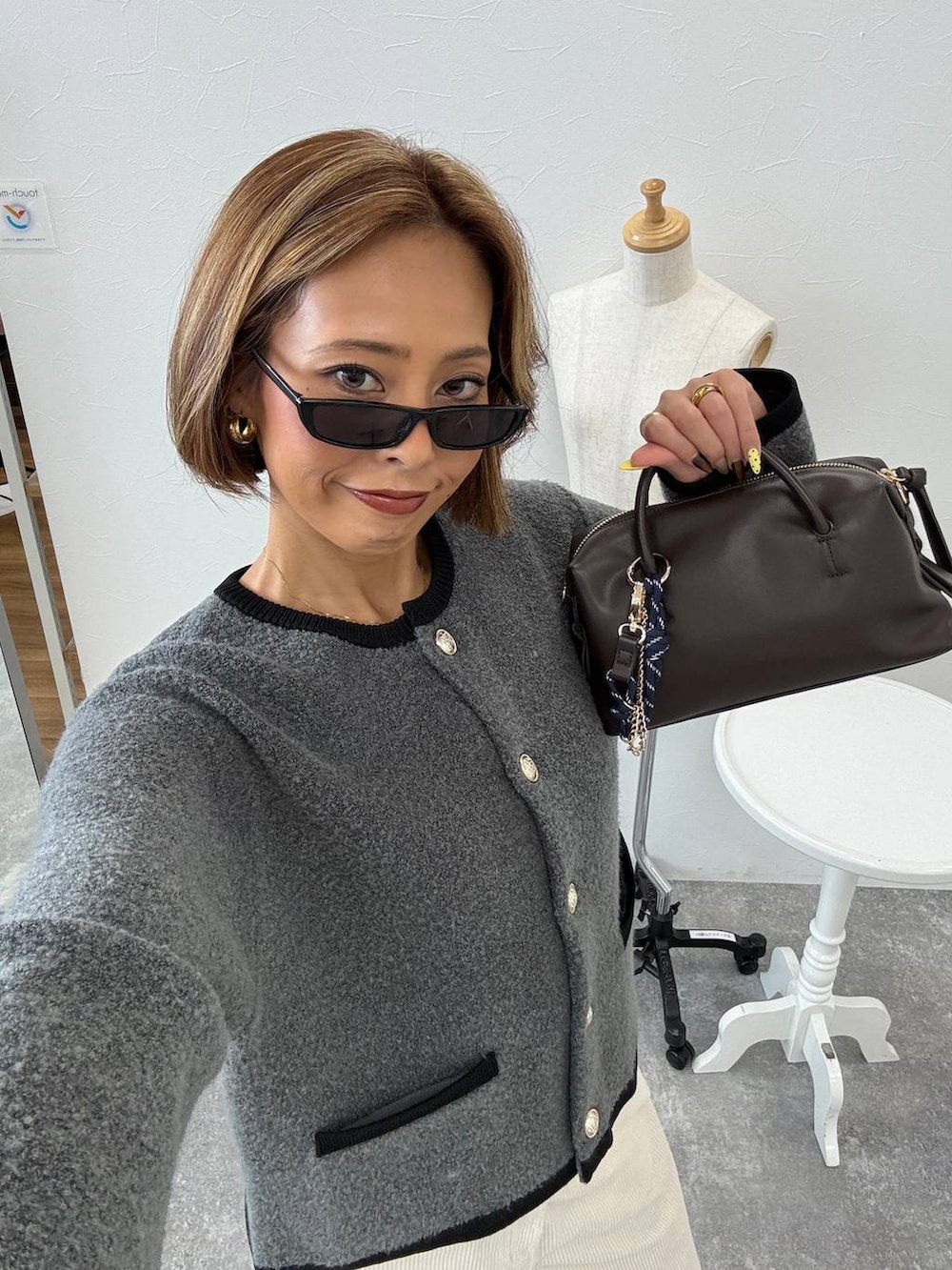 ホワイト系のその他パンツ、グレー系のノーカラージャケット、ブラウン系のボストンバッグを着用したレディースの秋コーディネートの2枚目の写真
