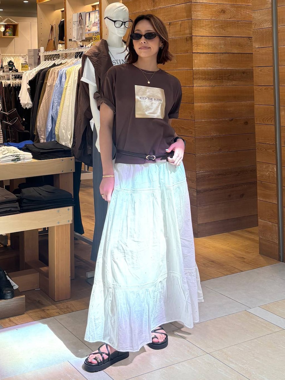 ホワイト系のスカート、ブラウン系のTシャツ/カットソー、ブラック系のサンダルを着用したレディースの春コーディネートの2枚目の写真