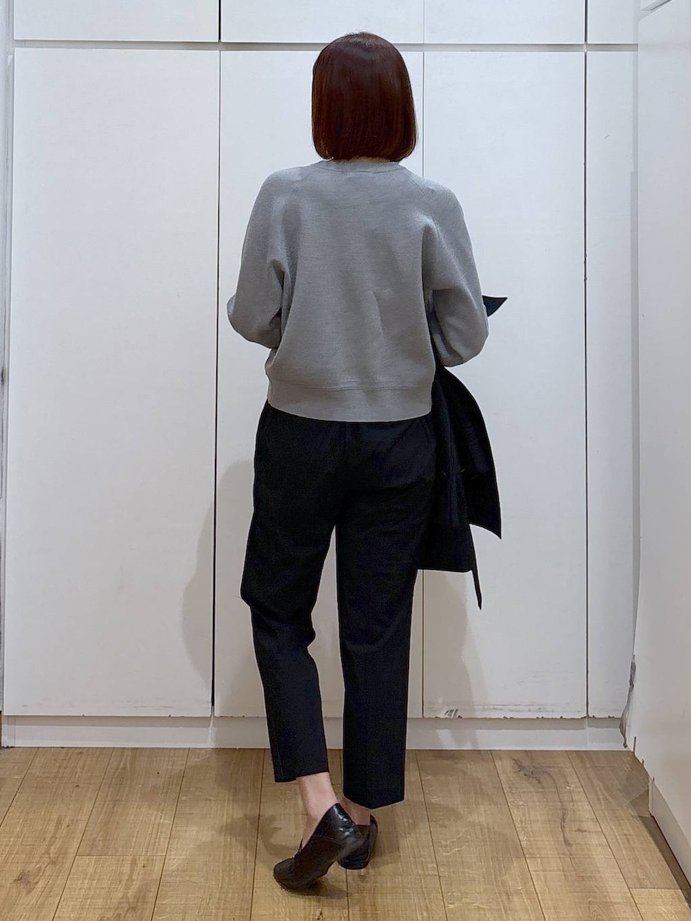 ブラック系のローファー、ブラック系のスラックス、ブルー系のトレンチコートを着用したレディースの春コーディネートの6枚目の写真