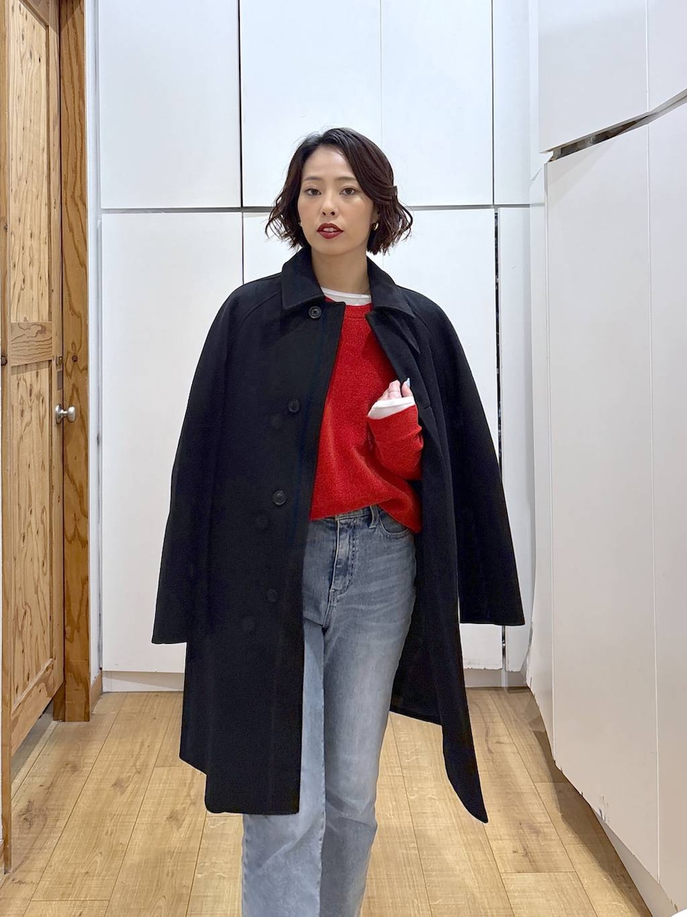 ブラック系のローファー、ブラック系のステンカラーコート、ブルー系のデニムパンツを着用したレディースの冬コーディネートの4枚目の写真