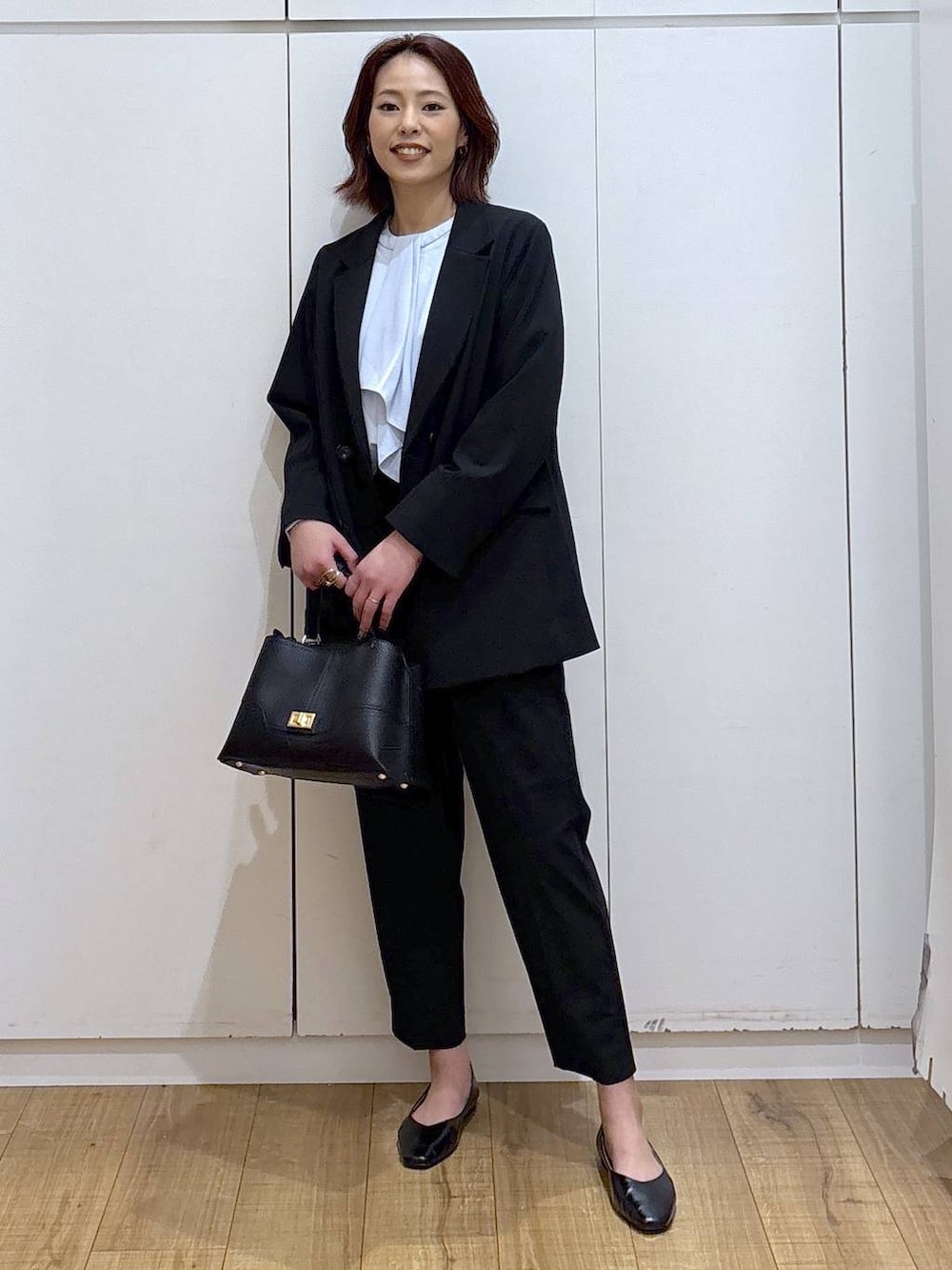ブラック系のパンプス、ブラック系のスラックス、ブルー系のシャツ/ブラウスを着用したレディースの春コーディネートの3枚目の写真