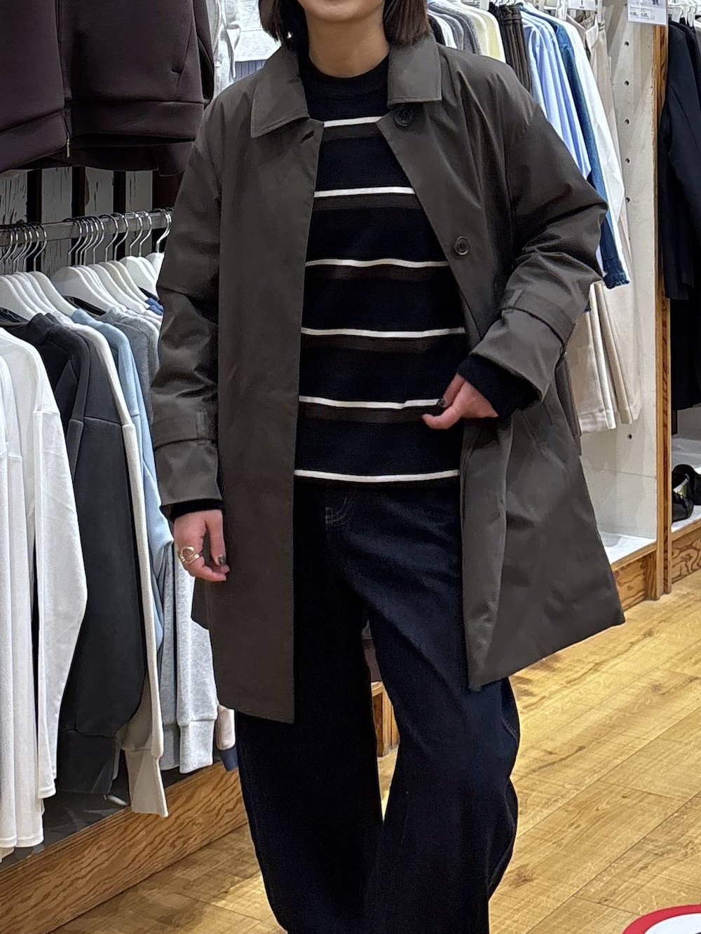 ブラウン系のステンカラーコート、ブルー系のデニムパンツを着用したレディースの冬コーディネートの2枚目の写真