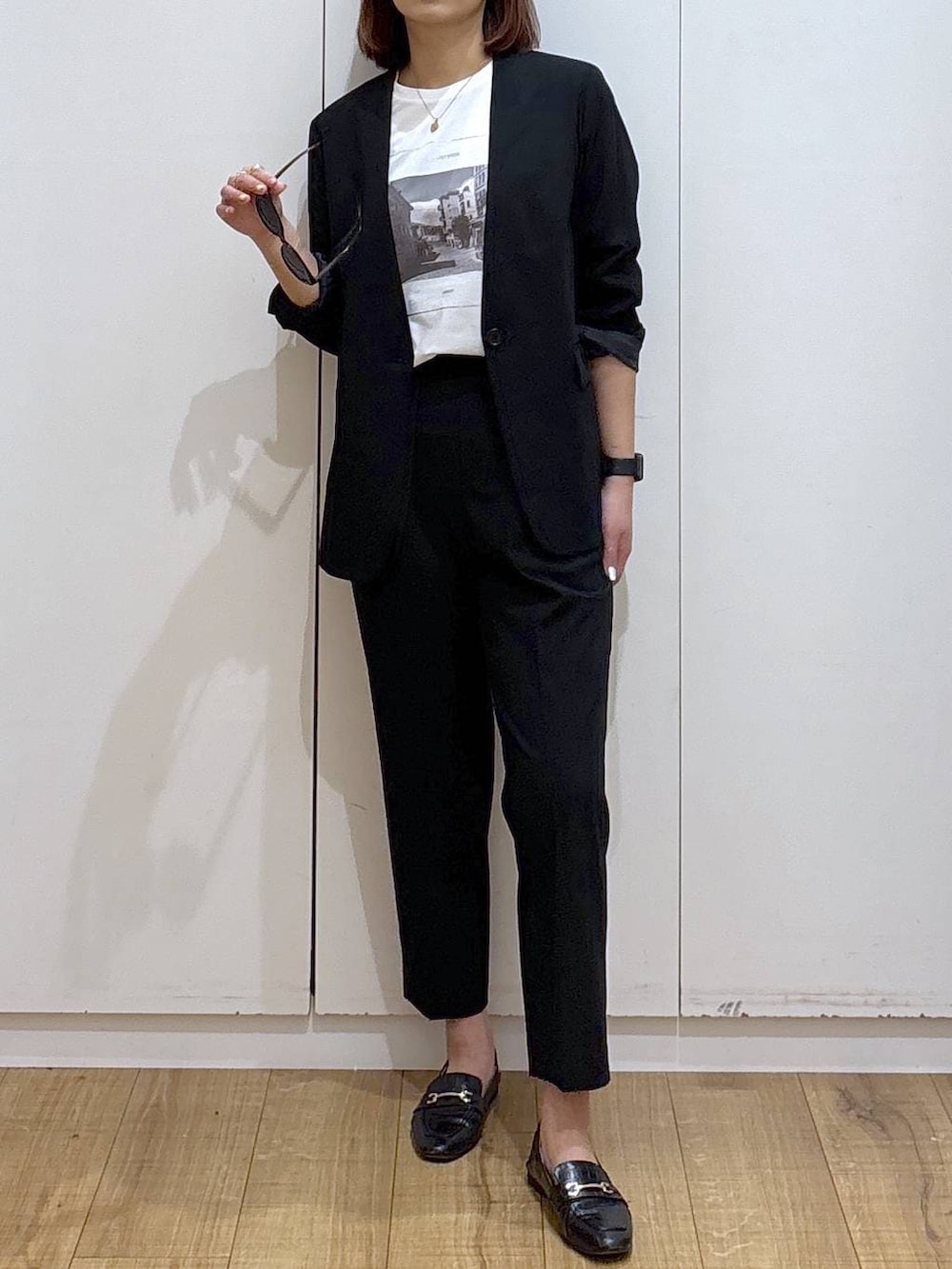 ブラック系のローファー、ブラック系のスラックス、ブラック系のノーカラージャケットを着用したレディースの春コーディネートの2枚目の写真