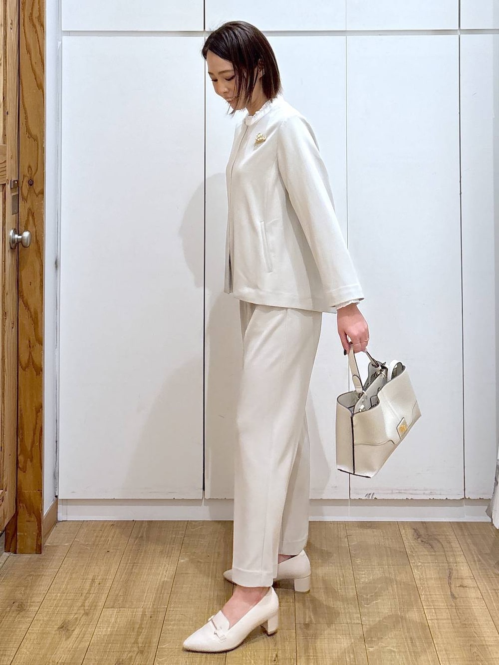 ベージュ系のセットアップ、ベージュ系のショルダーバッグ、ホワイト系のローファーを着用したレディースの冬コーディネートの6枚目の写真