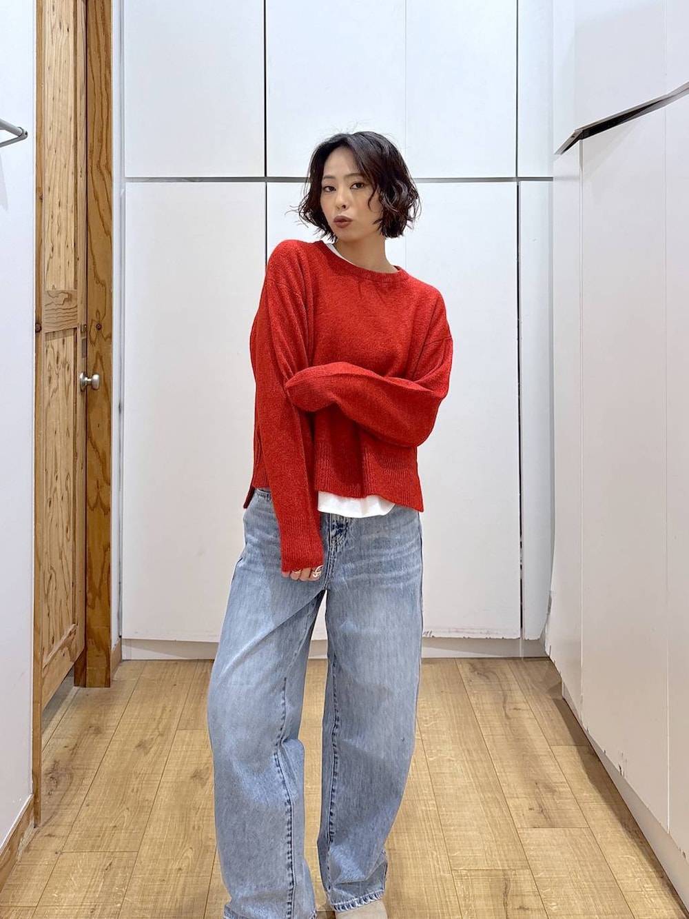 ブルー系のデニムパンツ、レッド系のニット/セーター、ホワイト系のTシャツ/カットソーを着用したレディースの冬コーディネートの5枚目の写真