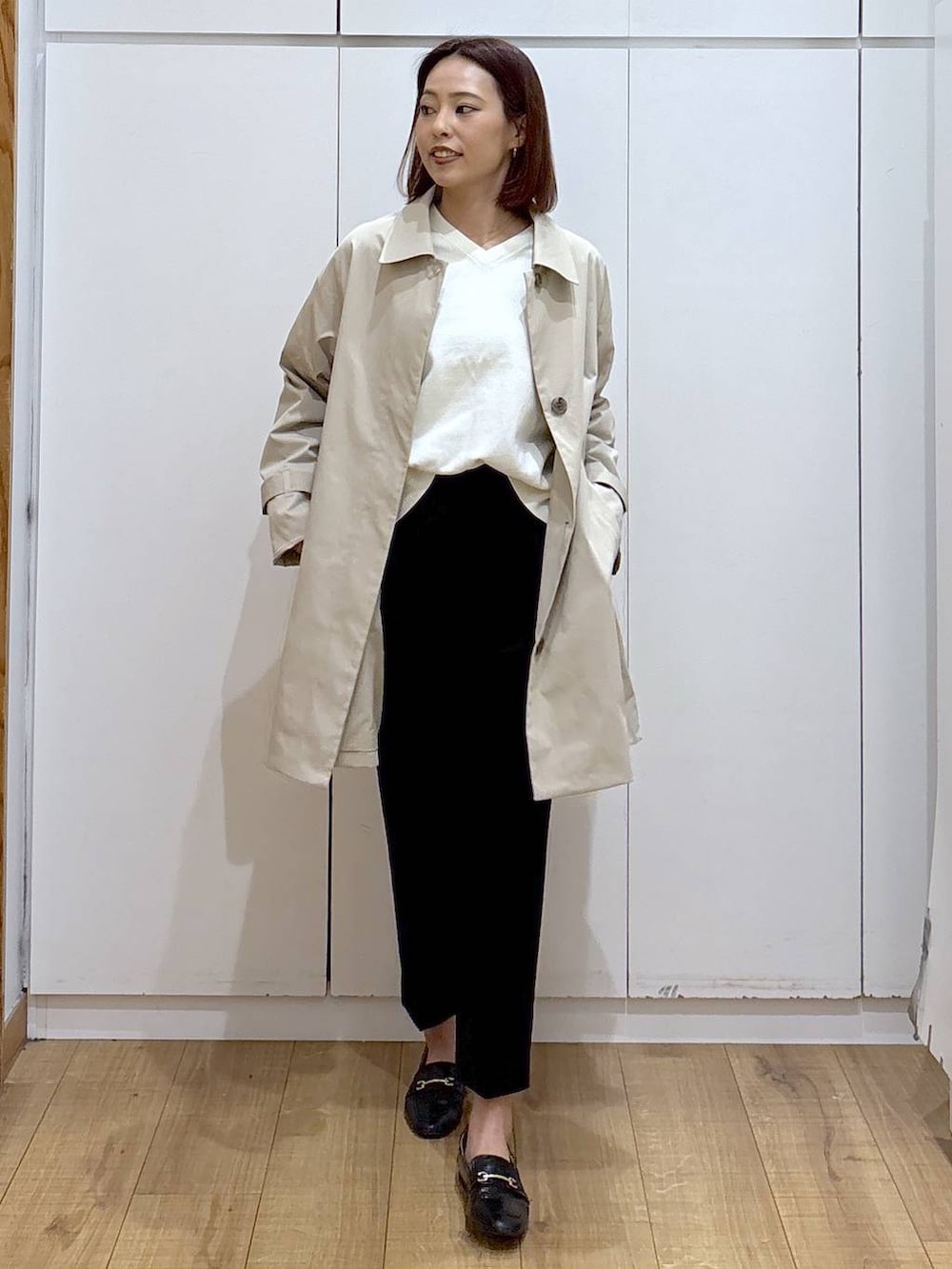 ブラック系のローファー、ブラック系のスラックス、ベージュ系のステンカラーコートを着用したレディースの春コーディネートの2枚目の写真