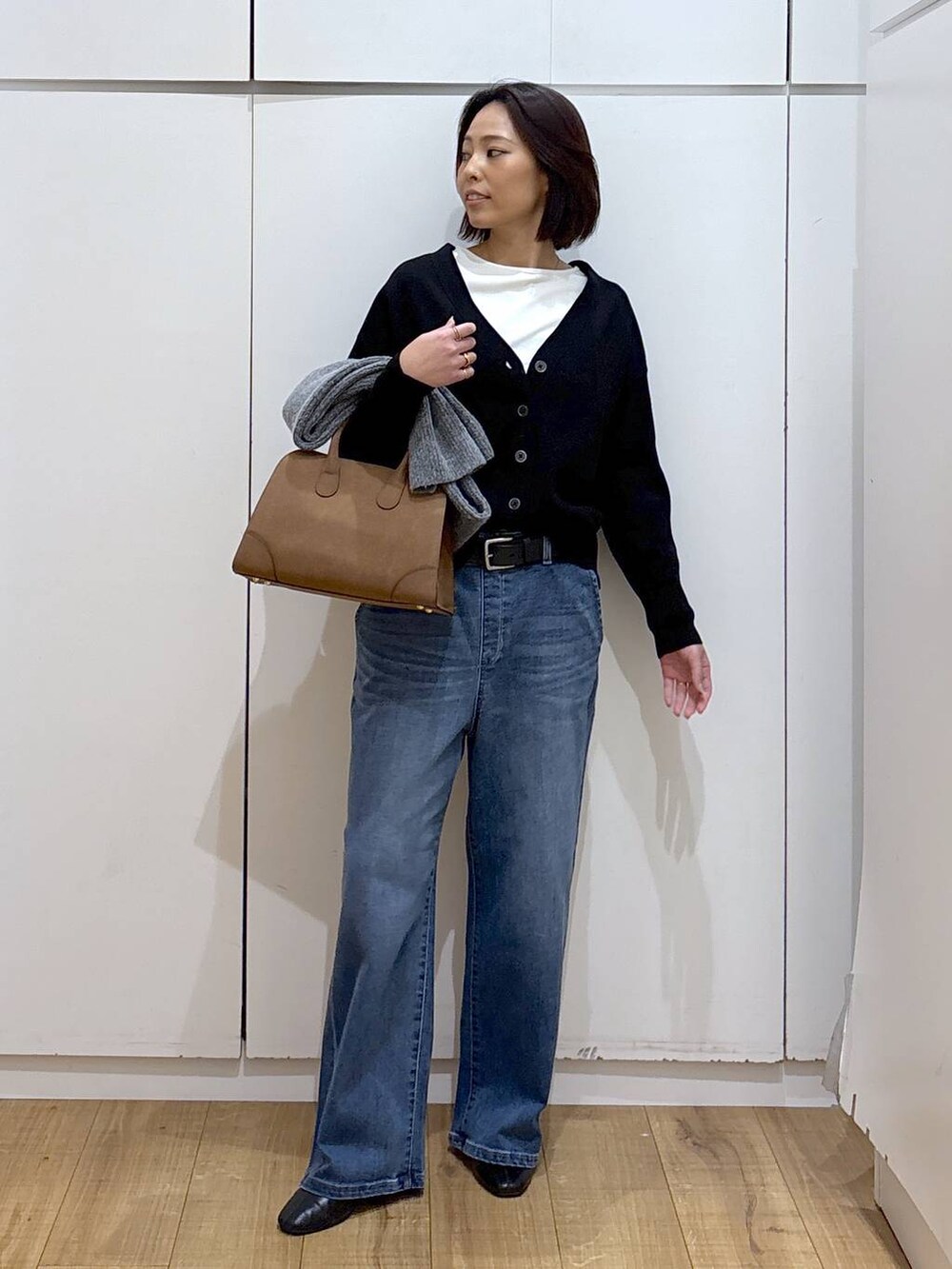 ブラック系のカーディガン/ボレロ、ベージュ系のショルダーバッグ、ブラック系のブーツを着用したレディースの秋コーディネートの3枚目の写真