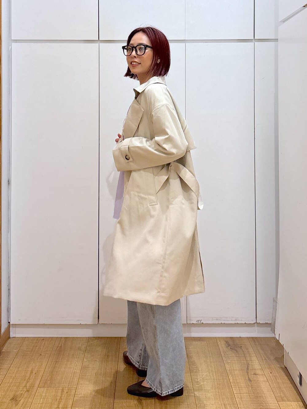 ホワイト系のベスト、ブルー系のデニムパンツ、ベージュ系のトレンチコートを着用したレディースの春コーディネートの3枚目の写真