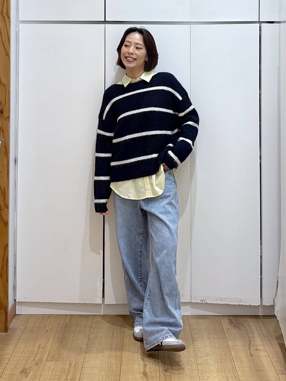 ブルー系のデニムパンツ、イエロー系のシャツ/ブラウス、ブルー系のニット/セーターを着用したレディースの冬コーディネートの2枚目の写真