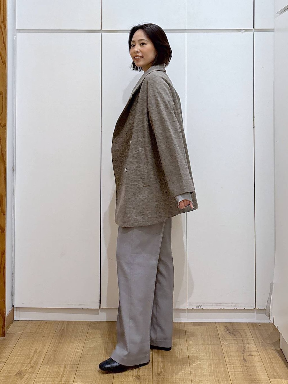 ブラウン系のチェスターコート、グレー系のその他パンツ、ホワイト系のTシャツ/カットソーを着用したレディースの秋コーディネートの3枚目の写真