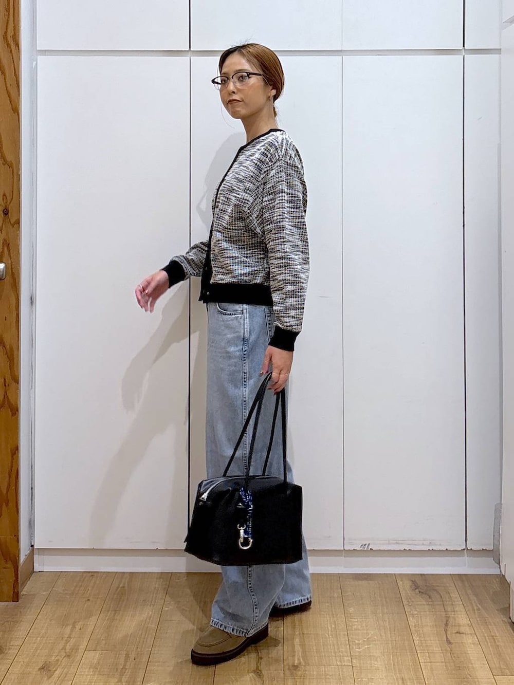 ブラック系のボストンバッグ、ブルー系のデニムパンツ、ベージュ系のローファーを着用したレディースの秋コーディネートの4枚目の写真