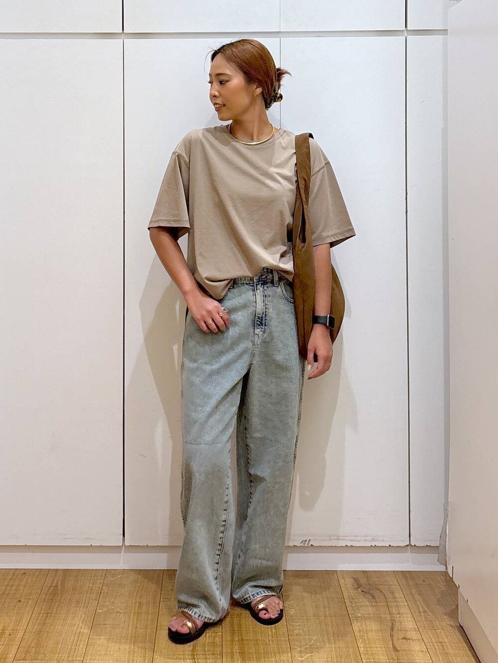 ブラウン系のサンダル、ベージュ系のTシャツ/カットソー、ブルー系のデニムパンツを着用したレディースの秋コーディネートの2枚目の写真