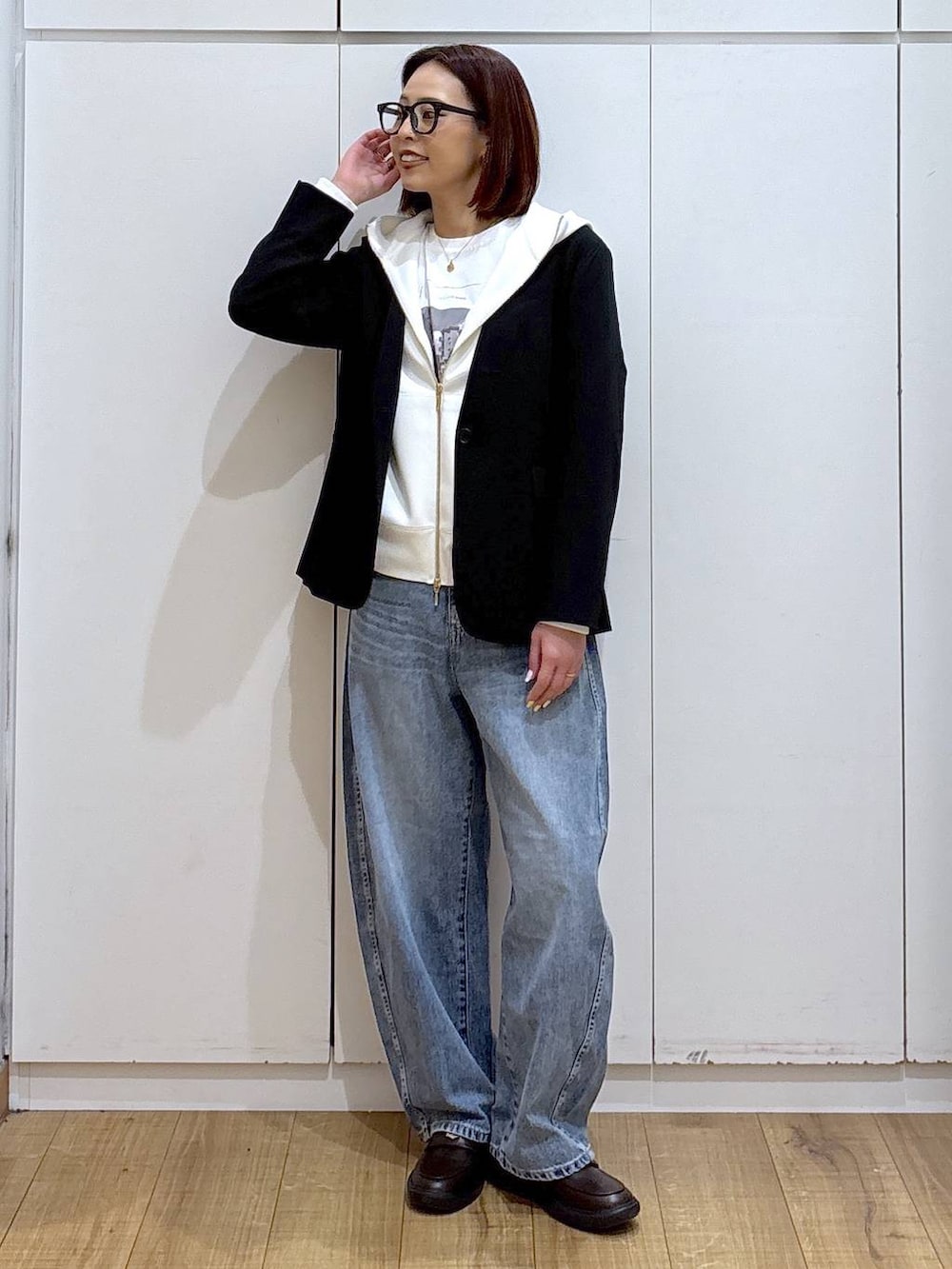 ホワイト系のパーカー、ブラック系のノーカラージャケット、ブルー系のデニムパンツを着用したレディースの春コーディネートの6枚目の写真