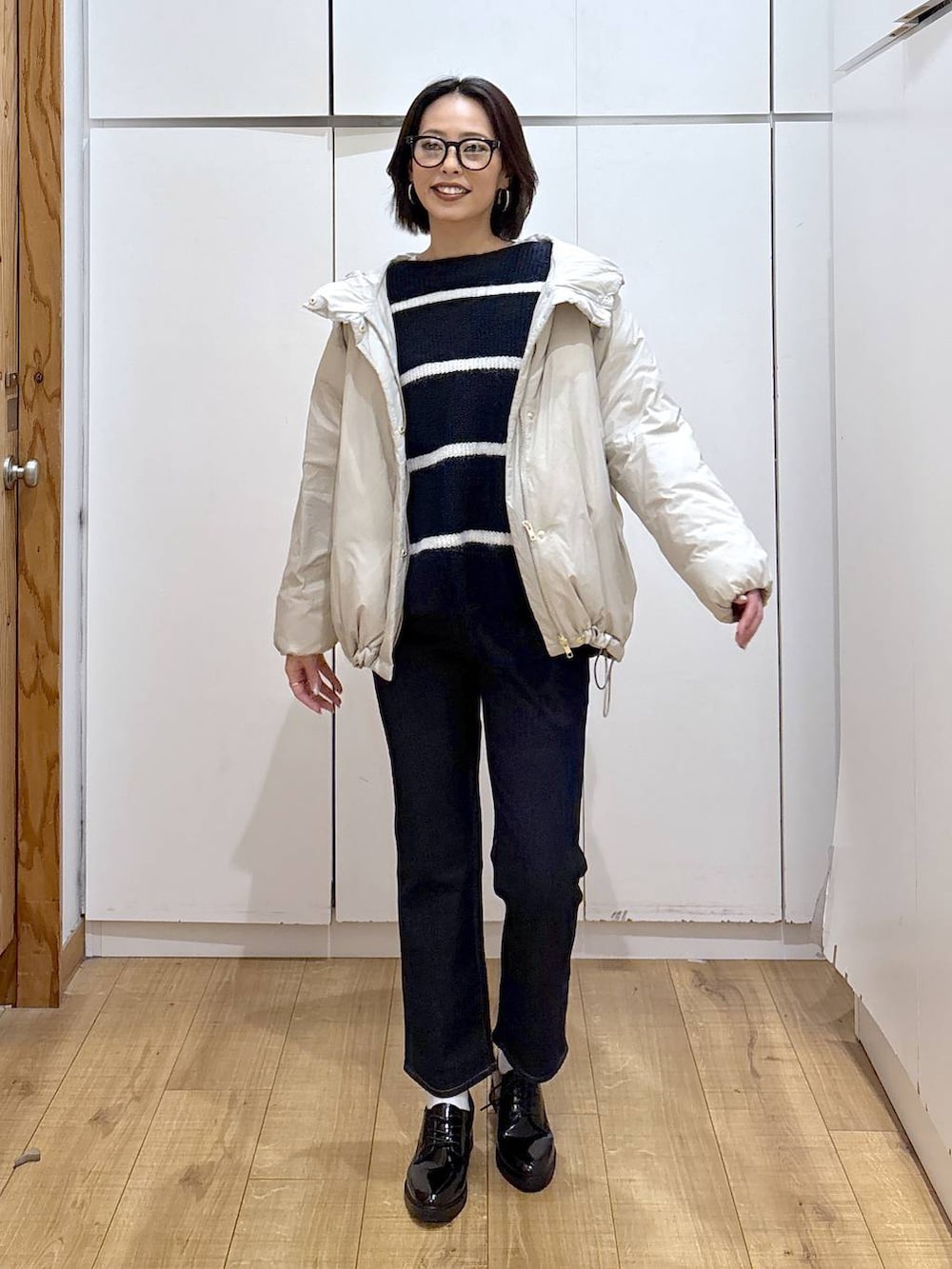 ベージュ系のダウンジャケット/コート、ブルー系のデニムパンツ、ブルー系のニット/セーターを着用したレディースの秋コーディネートの2枚目の写真