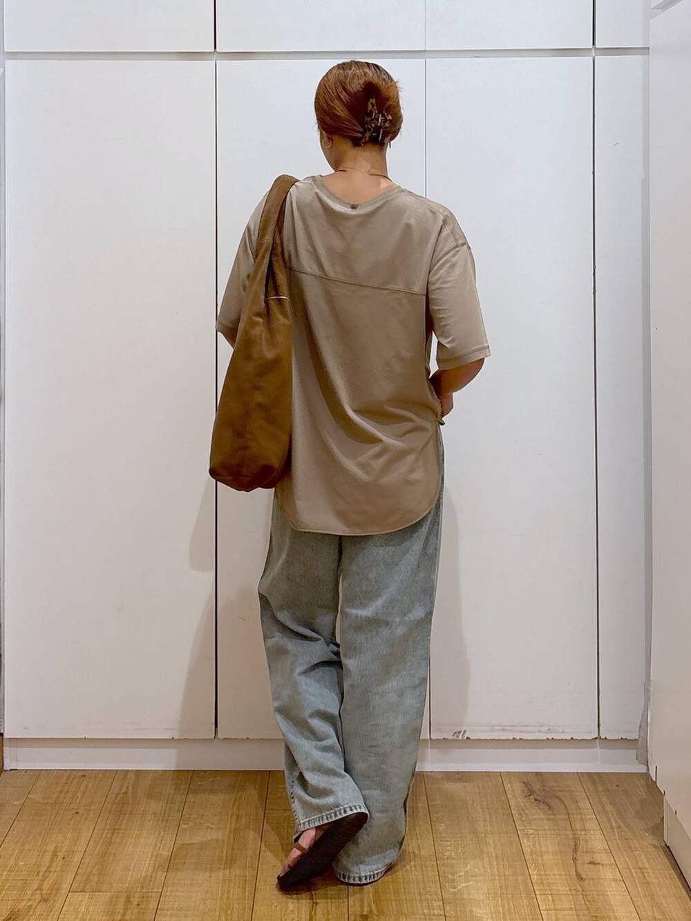 ブラウン系のサンダル、ベージュ系のTシャツ/カットソー、ブルー系のデニムパンツを着用したレディースの秋コーディネートの5枚目の写真
