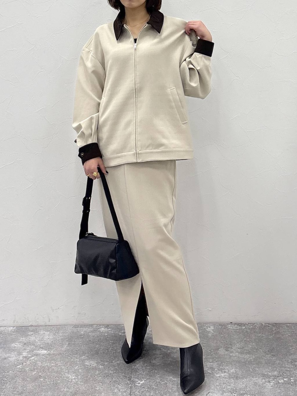 ブラック系のブーツ、ブラック系のショルダーバッグ、ベージュ系のスカートを着用したレディースの冬コーディネートの2枚目の写真