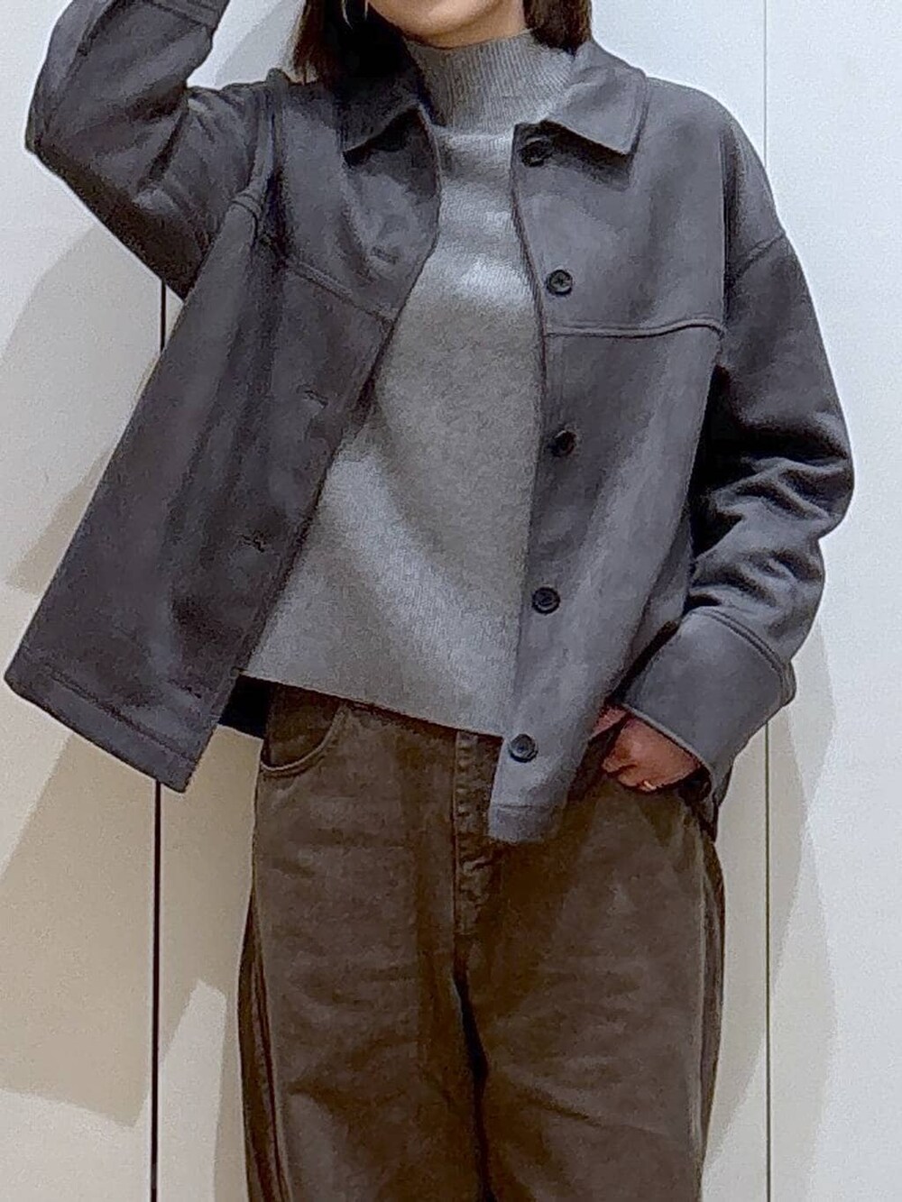 グレー系のニット/セーター、グレー系のテーラードジャケット、ブラウン系のデニムパンツを着用したレディースの冬コーディネートの3枚目の写真