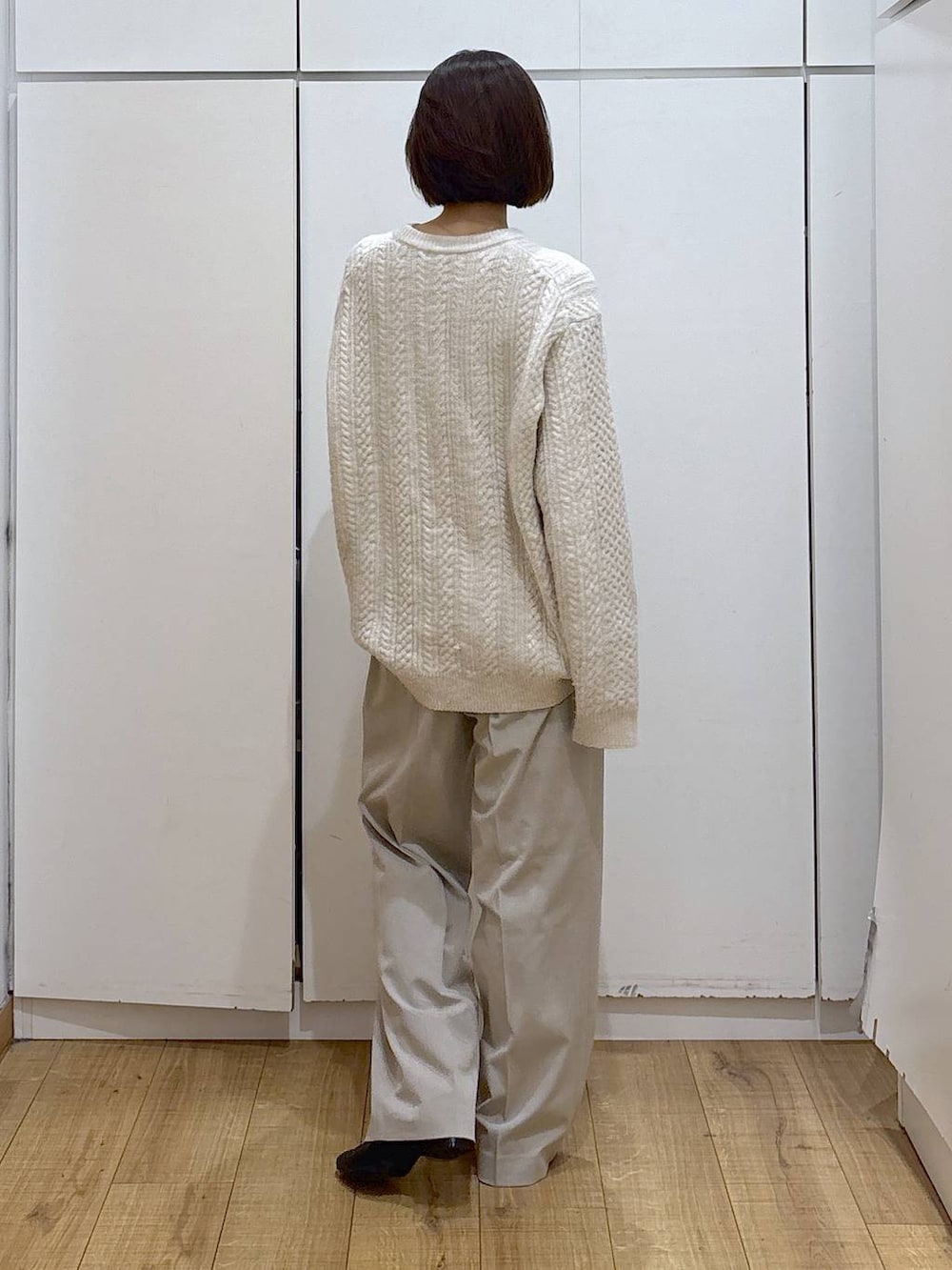 ベージュ系のスラックス、ブラック系のブーツ、ホワイト系のニット/セーターを着用したレディースの冬コーディネートの5枚目の写真